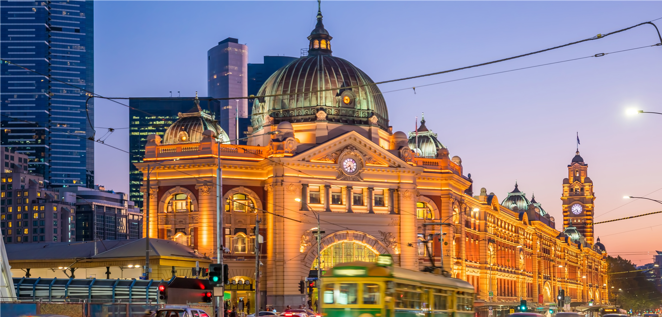 A tram passes by Melbourne’s Flinders Street Station at sunset.